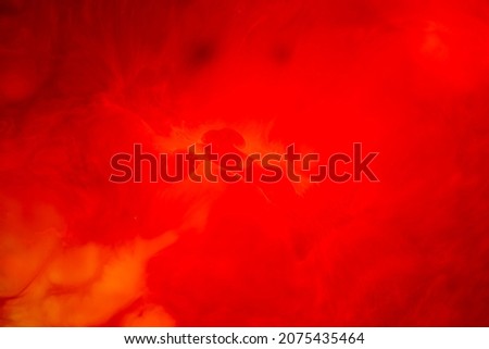 Abstract red shadowy background of swirls with an abstract pattern of bubbles created by a mixture of paint colours in a milk base.