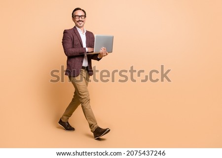 Full length body size view of attractive cheerful skilled man going using laptop copy empty space isolated over beige color background Royalty-Free Stock Photo #2075437246