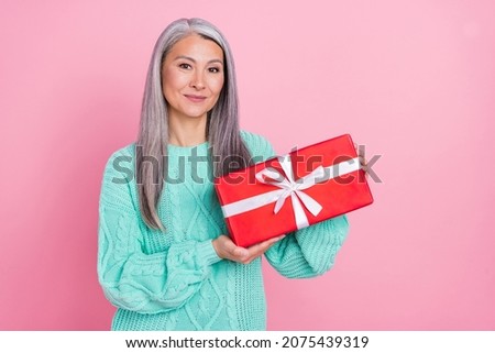 Photo of optimistic white hairdo old lady hold gift wear scarf teal sweater isolated on pink color background