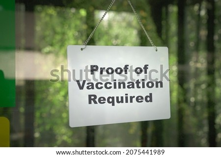 Signboard, Proof of Vaccination Required hanging on the door front of a shop. No vaccine, no entry concept.