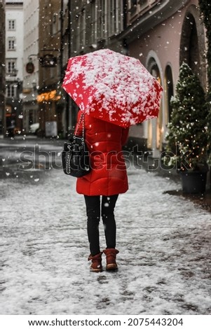 Girl in red with a red umbrella. Snowing. Winter. New Year. Christmas.