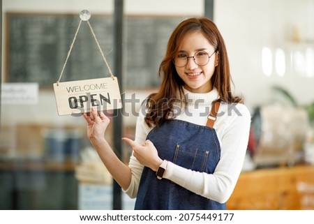 Portrait of a Asian woman, beautiful smiling, starting small business owner with apron near window in her cafe.