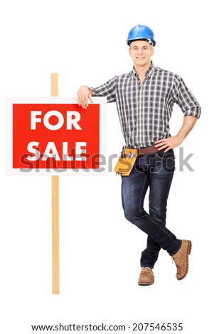 Full length portrait of a male repairman leaning on a for sale sign isolated on white background