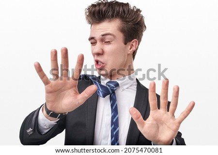 Funny male entrepreneur in formal suit showing stop sign with reached out hands on white background in studio