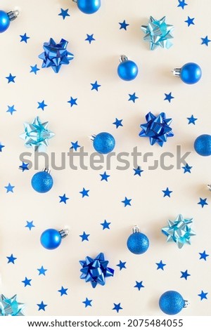 Christmas blue ornament decoration background. Blue bauble, ribbons and stars on a beige wallpaper.