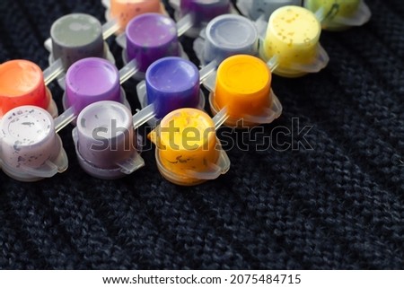 jars with liquid for drawing and painting inside on a woolen black background in soft focus for the design of children's creative websites; letters and words can be inserted into the barrels