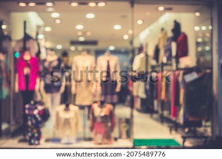 Blur image of boutique window with dressed mannequins. Boutique display window with mannequins in fashionable dresses. Toned image. Royalty-Free Stock Photo #2075489776