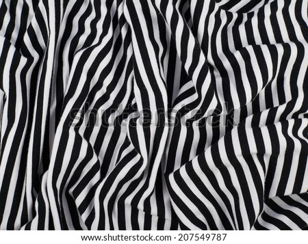 Fragment of a striped wrinkled black and white piece of a cloth fabric as a background texture