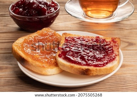 Toasts with red and orange jam on white plate. Royalty-Free Stock Photo #2075505268