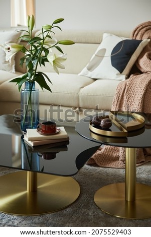 Glamorous living room interior design with modern beige sofa, glass coffee table and golden accessories. Beauty in the details. Template.  Royalty-Free Stock Photo #2075529403