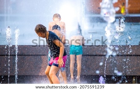  Children frolic in the jets of the city fountain in the summer heat