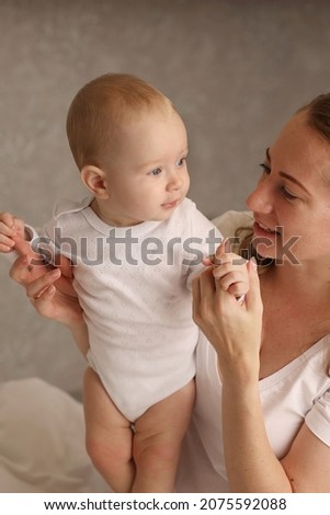 Hugs of mom and a cute blonde baby on a white bed. motherhood. breastfeeding. High-quality photography