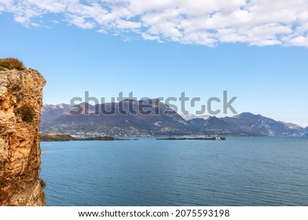 Rocky coast of Lake Garda and a view of the small islands (Autumn season)