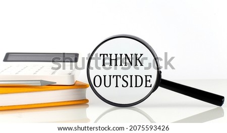 Magnifier with text THINK OUTSIDE with notebook, calculator on white background