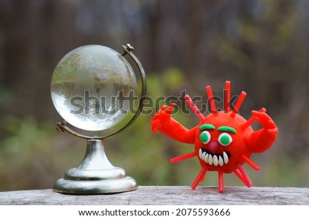 A virus figurine and a glass globe close-up. Infection of the planet.