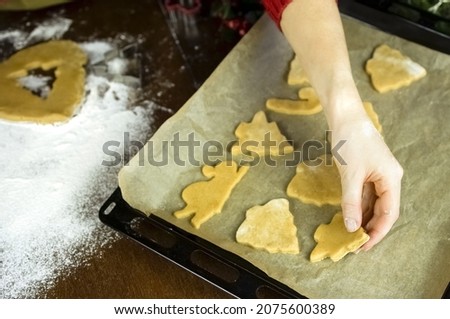 The man lays down the cookies for baking on the baking sheet. Delicious, healthy, beautiful food for the Christmas holiday.