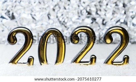Gold numbers 2022 on white background with snow. New year backdrop with 2022 year