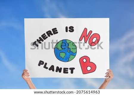 Protestor holding placard with text There Is No Planet B against blue sky, closeup. Climate strike