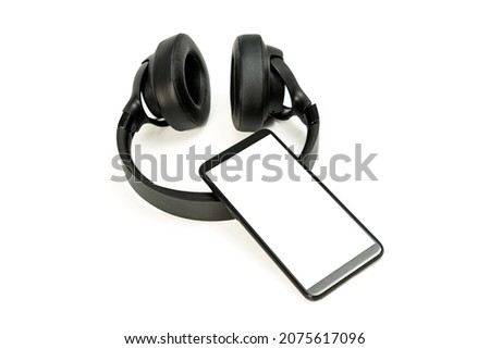black wireless headphones and smartphone on white background, blank screen mockup, copy space