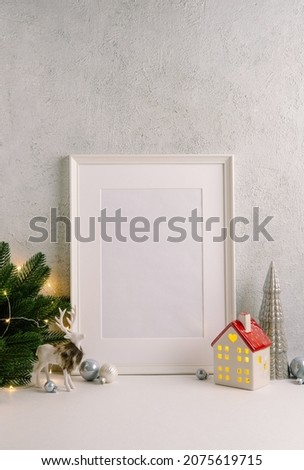 Christmas composition of Christmas decorations, pine branches, House lantern and a white mock up poster frame for presentation of works and text. Template.
