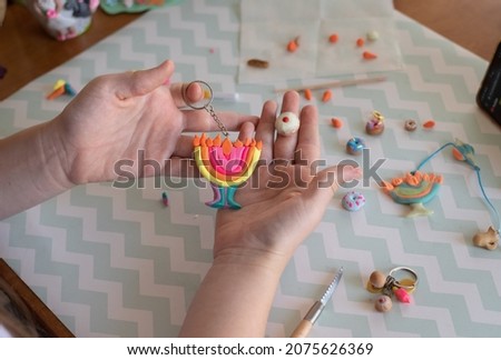 Hands of child hold Hanukkah make from plasticine with candles and donut. Traditional Jewish holiday - Hanukkah. learning online play with polymer clay. Handmade miniature, souvenirs. study on phone
