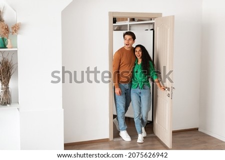 Wow. Portrait of excited emotional couple walking in their apartment, entering new home, happy young guy and lady standing in doorway of modern flat, looking at design interior together, coming inside Royalty-Free Stock Photo #2075626942