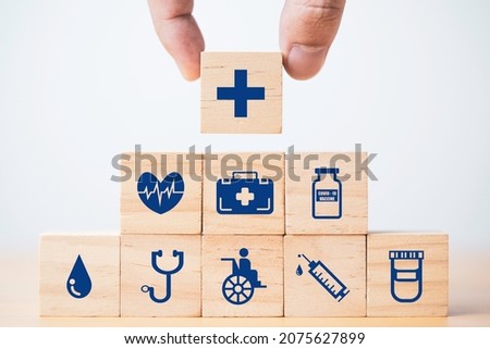 Hand putting and stacking Healthcare and medical icons which print screen on wooden cube block for health insurance concept.