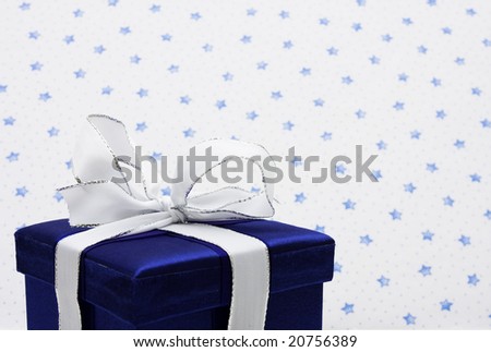 Blue present wrapped with white bow on snow with star background, holiday present