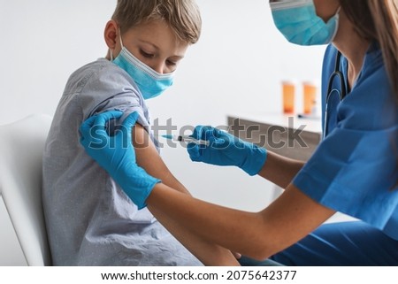 Kids Vaccination. Nurse Injecting Covid-19 Vaccine Vaccinating Boy In Arm For Virus Protection In Clinic. Preteen Child Getting Vaccinated Against Coronavirus Wearing Face Mask. Cropped Royalty-Free Stock Photo #2075642377