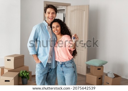 Mortgage and Relocation Concept. Portrait of happy woman hugging man, holding key from new first house, young family celebrating moving day, satisfied customers buyers couple purchase real estate Royalty-Free Stock Photo #2075642539