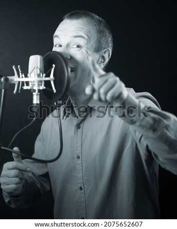 Voiceover artist voice actor in vocal recording studio with larg diaphragm microphone and antipop shield.
