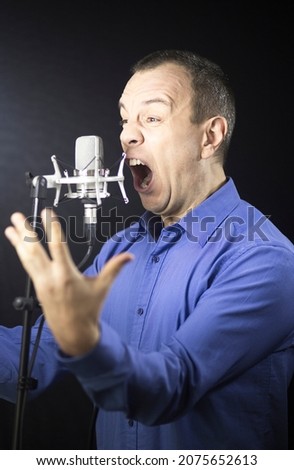 Voiceover artist voice actor in vocal recording studio with larg diaphragm microphone and antipop shield.