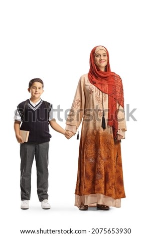 Full length portrait of an arab woman in a hijab holding hands with a schoolboy in a uniform isolated on white background