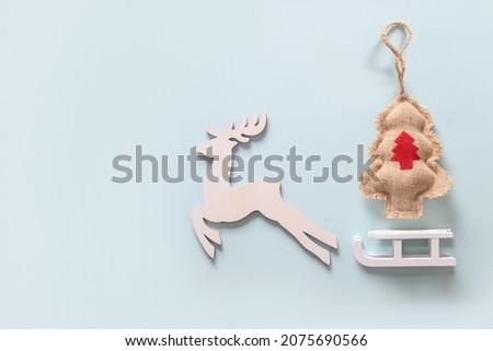 Christmas flat lay composition with white wooden reindeer, Christmas tree and sleigth on blue background. Banner. Greeting card with copy space.