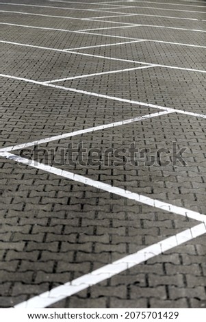 Parking road marking on brick pavement without cars. White road surface marking lines in car parking, marked free parking spaces. White geometric lines separating space