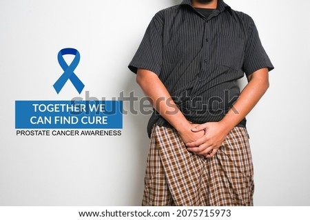 Selective focus picture of blue ribbon and together we can find cure, prostate cancer awareness with men holding private part with cloth insight.