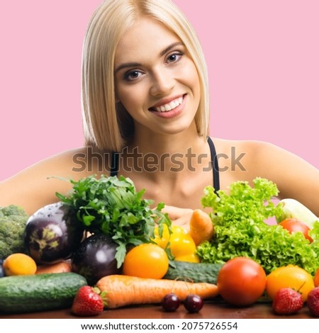 Healthy eating and vegan diet studio concept image - portrait of happy smiling beautiful blond woman with vegetarian food, fruits and vegetables, over rose pink color background.