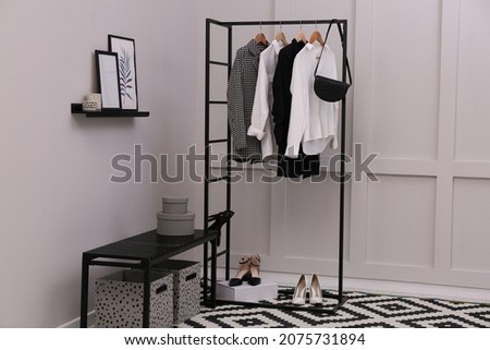 Rack with stylish women's clothes and bench in dressing room