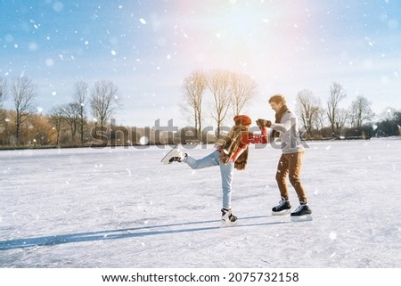 Loving couple in warm sweaters having fun on ice. Woman and man ice skating outdoors in sunny snowy day. Active date on ice arena in winter Christmas Eve. Romantic activities and lifestyle concept.