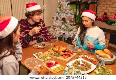 Group of Friends Enjoying Christmas Drinks  at home.Winter holidays concept.Happy friends are having dinner at home. Celebration holiday and togetherness near tree.Party  with glasses of champagn