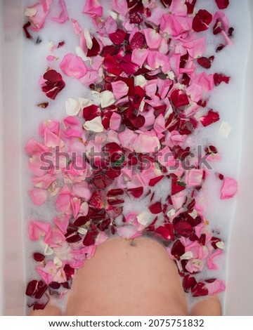 Man takes a bath with milk and rose petals.