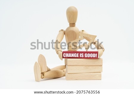 Business and Economics. On a white background, a wooden man sits near the wooden blocks, he holds in his hands a red block with the inscription - Change is Good