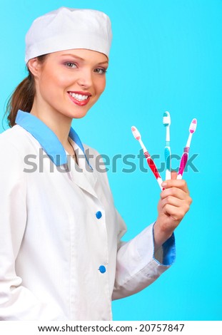 Smiling doctor with tooth-brushes. Over blue background