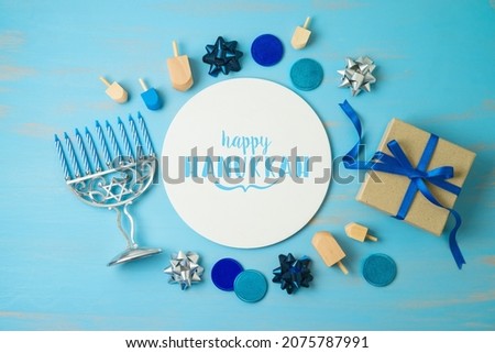 Hanukkah holiday concept with menorah, gift box and spinning top on blue background. Top view from above
