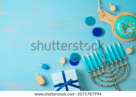 Flat lay composition for Jewish holiday Hanukkah  with traditional donuts, menorah and gift box on wooden table