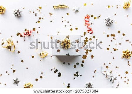 Gift white box with a gold tape with tinsel and confetti on a white background. The concept of a gift, a new year, a festive background. Flat lay, top view Royalty-Free Stock Photo #2075827384