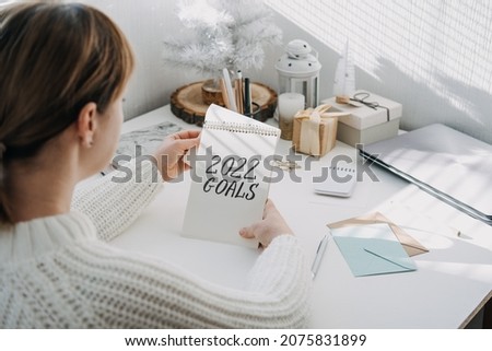 2022 goals, New year resolution. Woman in white sweater writing Text 2022 goals in open notepad on the table. Start new year, planning and setting goals for the next year Royalty-Free Stock Photo #2075831899