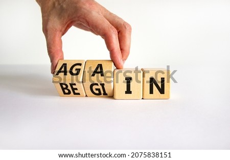 Begin again symbol. Businessman turns wooden cubes and changes the word begin to again. Beautiful white table, white background. Business and begin again concept. Copy space.