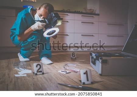 Forensic specialist in protective suit taking photos on a crime scene
