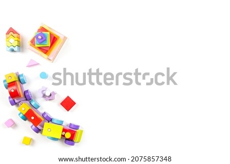 Baby kids toys background. Top view to wooden toy train, wood stacking pyramid tower and colorful wood bricks on white background. Early education, zero waste, Montessori toys for children Royalty-Free Stock Photo #2075857348